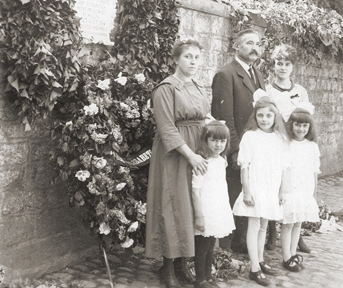 Eine Familie an der Mauer im belgischen Dinath, an der deutsche Truppen Bewohner des Ortes im August 1914 hinrichteten