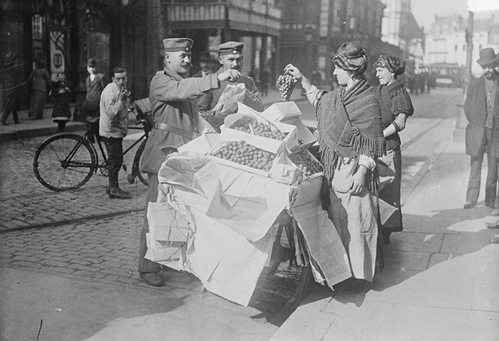 Deutsche Soldaten kaufen Obst an einem Stand im besetzten Belgien